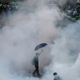 A protester walks in tear gas fired by riot policemen after thousands of protesters blocking the main street to the financial Central district outside the government headquarters in Hong Kong September 28, 2014.
